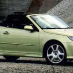 En grön Saab C1 roadster parkerad på grus. (AI text)