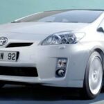 En vit Toyota Prius kör nerför en väg. (AI text)