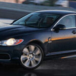 En Jaguar XF kör på en blöt bana. (AI text)