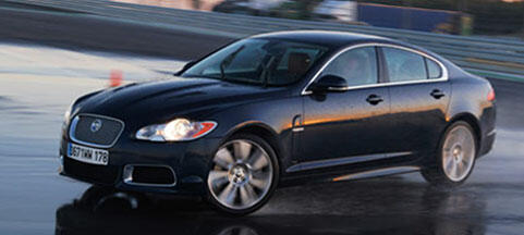 En Jaguar XF kör på en blöt bana. (AI text)
