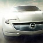 En vit bil kör på en väg. (AI text)