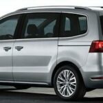 En silverfärgad Volkswagen Touran parkerad på en gata. (AI text)