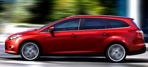 En röd Ford Focus kör nedför en stadsgata. (AI text)