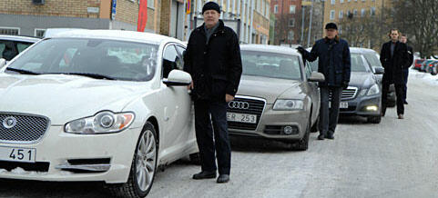 En grupp personer står bredvid en rad bilar. (AI text)