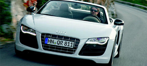 En Audi R8 Spyder kör nerför en bergsväg. (AI text)