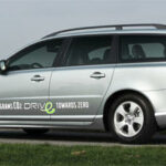 En silverfärgad Volvo V70 parkerad vid en gräsmattad väg. (AI text)