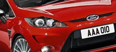 En röd Ford Fiesta parkerad i en parkeringsplats. (AI text)