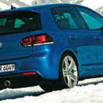En blå Volkswagen Golf R körande i snö. (AI text)