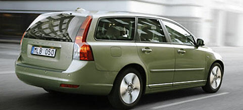 En grön Volvo V60 står och kör ner en stadsgata. (AI text)