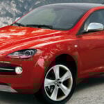 En röd Alfa Romeo SUV parkerad framför ett berg. (AI text)