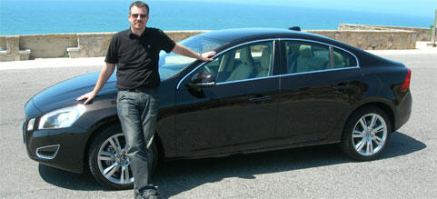 En man står bredvid en Volvo S60. (AI text)