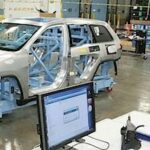 En man arbetar på en bil i en fabrik. (AI text)