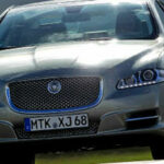 En Jaguar XF kör nedför en väg. (AI text)