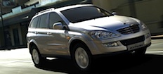 En silverfärgad SUV kör nerför en stadsgata. (AI text)