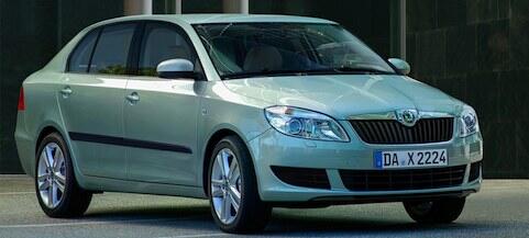 En grön Skoda Saturn parkerad framför ett byggnad. (AI text)