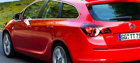 En röd Opel Astra kör längs en landsväg. (AI text)