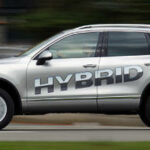 En silverfärgad Porsche Cayenne hybrid kör längs vägen. (AI text)