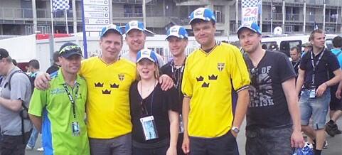 En grupp personer poserar för ett foto vid en racerbana. (AI text)