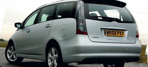 En silverfärgad bil står parkerad vid en vägkant. (AI text)