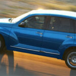 En blå Chrysler PT Cruiser kör nerför en väg. (AI text)