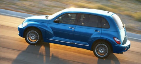 En blå Chrysler PT Cruiser kör nerför en väg. (AI text)