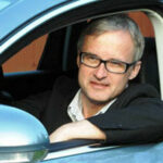 En man sitter i en bil. (AI text)