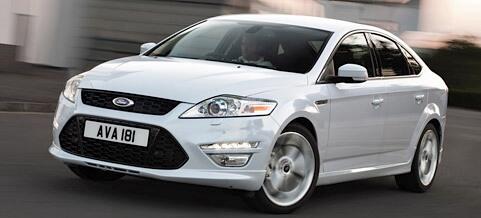 En vit Ford Mondeo kör längs vägen. (AI text)