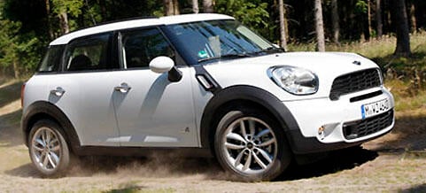 En vit Mini Countryman kör på en grusväg. (AI text)