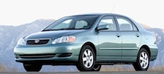 En gröna Toyota Corolla parkerad vid en vägkant. (AI text)