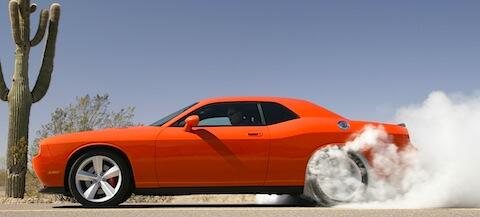 En Dodge Challenger kör längs en ökenväg. (AI text)