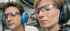 En man och kvinna i öronskydd tittar på en kamera. (AI text)