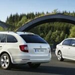 Två vita Skoda-bilar parkerade vid en gata. (AI text)