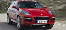 En röd Porsche Cayenne kör längs en väg. (AI text)