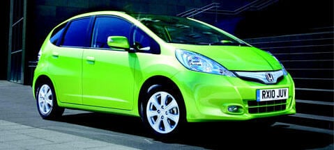 En grön Honda Fit parkerad på en gata (AI text)