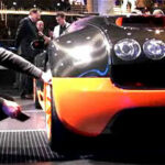 En man knäböjd bredvid en Bugatti Veyron. (AI text)