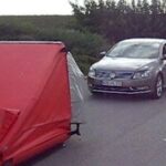En bil är parkerad på en gata med ett rött tält. (AI text)
