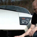 En man knorrar bredvid en vit Lamborghini. (AI text)
