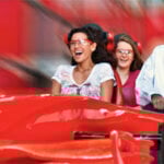 En grupp personer åker i en röd bil på en nöjespark. (AI text)