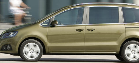 En grön Volkswagen Touran kör ner en gata. (AI text)