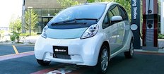 En liten elbil parkerad framför en bensinstation. (AI text)