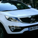 En vit SUV kör nerför en stadsgata. (AI text)