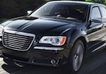 En svart Chrysler 300 kör nerför vägen. (AI text)