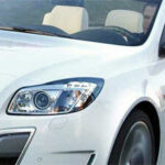 En vit Opel cabriolet kör nedför vägen. (AI text)