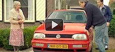 En man och en kvinna står bredvid en röd Volkswagen Golf. (AI text)