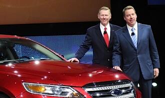 Två män står bredvid en bil. (AI text)