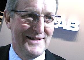 En man i kostym och slips står framför en bil. (AI text)