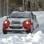 En rallybil kör genom snön. (AI text)