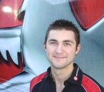 En man i rött skjortklädsel står framför en röd och vit lastbil. (AI text)