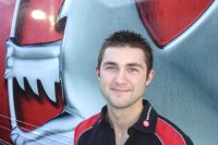 En man i rött skjortklädsel står framför en röd och vit lastbil. (AI text)