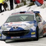 En rallybil kör nedför en snöig backe. (AI text)
